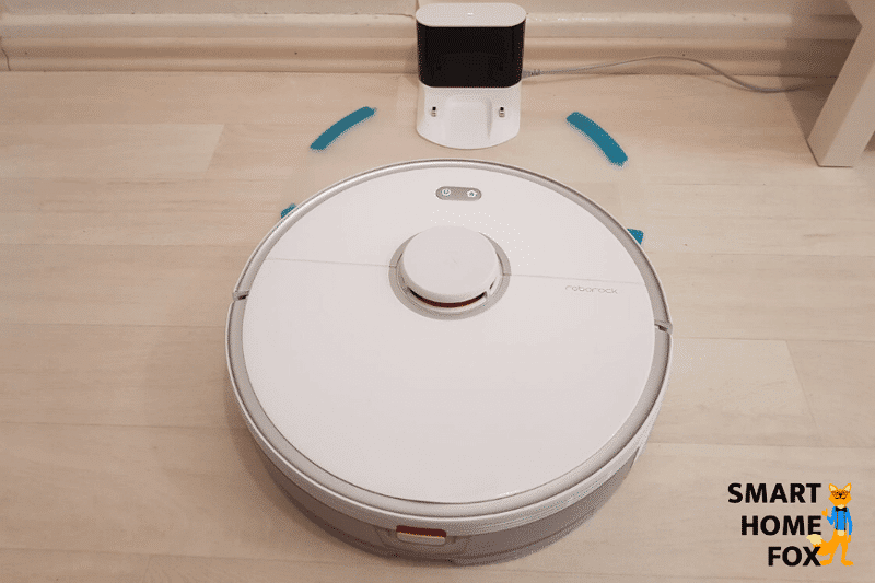 A robot vacuum mop combo stands at the charging dock on a plastic mat